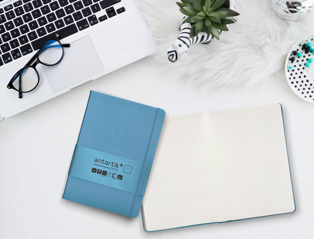 CUADERNO CON GOMILLA ANTARTIK NOTES TAPA DURA A5 HOJAS PUNTOS AZUL CLARO 100 HOJAS 80 GR FSC